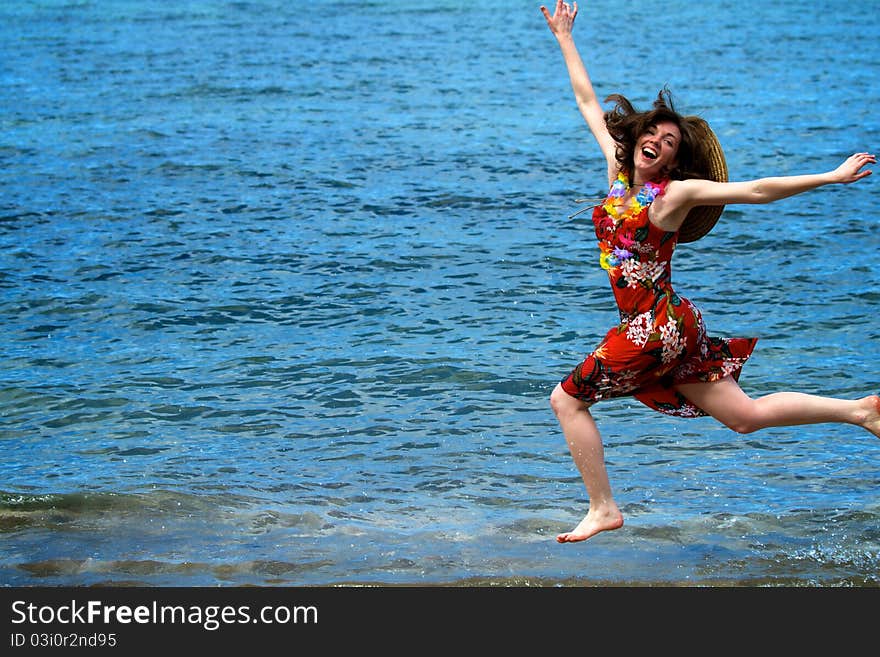 A woman jumps along the shoreline of a Maui beach, happy and excited to be on vacation in Hawaii. A woman jumps along the shoreline of a Maui beach, happy and excited to be on vacation in Hawaii.