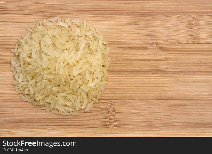 Pile of raw rice on wooden table, view from the top