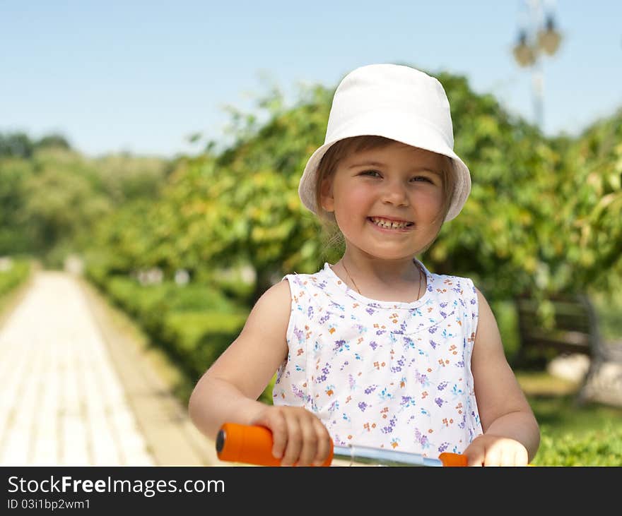 Little adorable girl posing with orange scooter in the park. Little adorable girl posing with orange scooter in the park