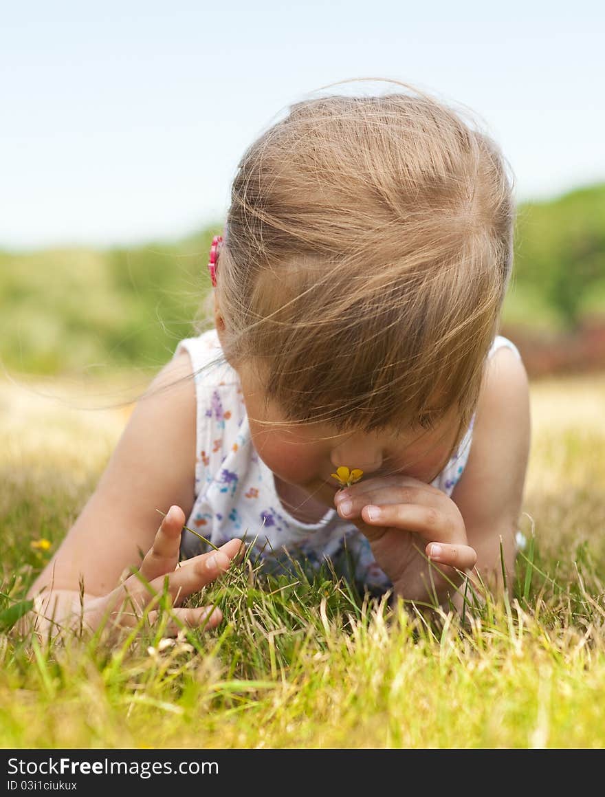 Little girl olfact flower and lying on grass in the park. Little girl olfact flower and lying on grass in the park