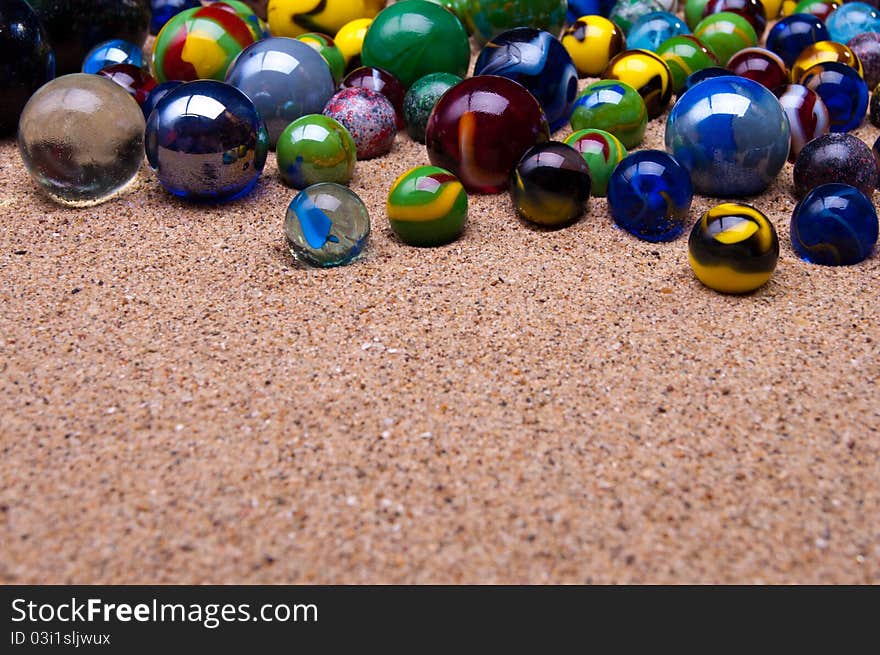 Colored glass marbles on a sandy background