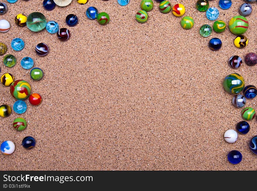 Colored glass marbles on a sandy background