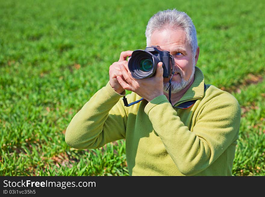 Photographer on green field holding camera. Photographer on green field holding camera