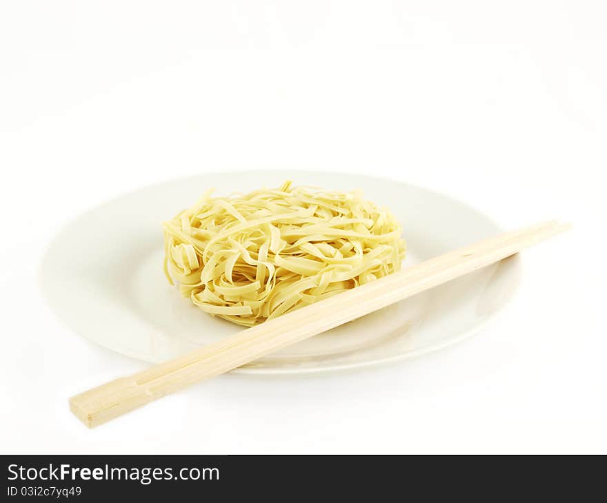 Dried uncoocked noodles, on white plate with chopsticks, isolated towards white background