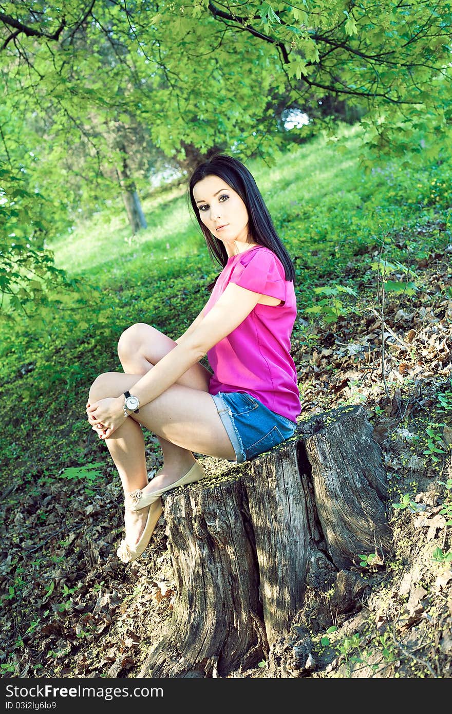 Elegant woman sitting on a stump