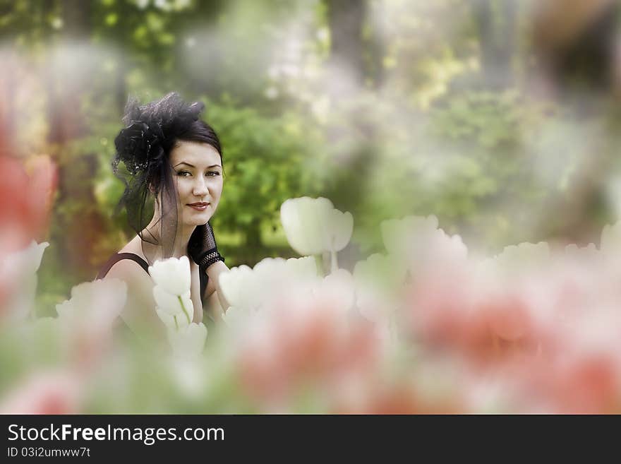 A girl in an elegant hat among the tulips. A girl in an elegant hat among the tulips