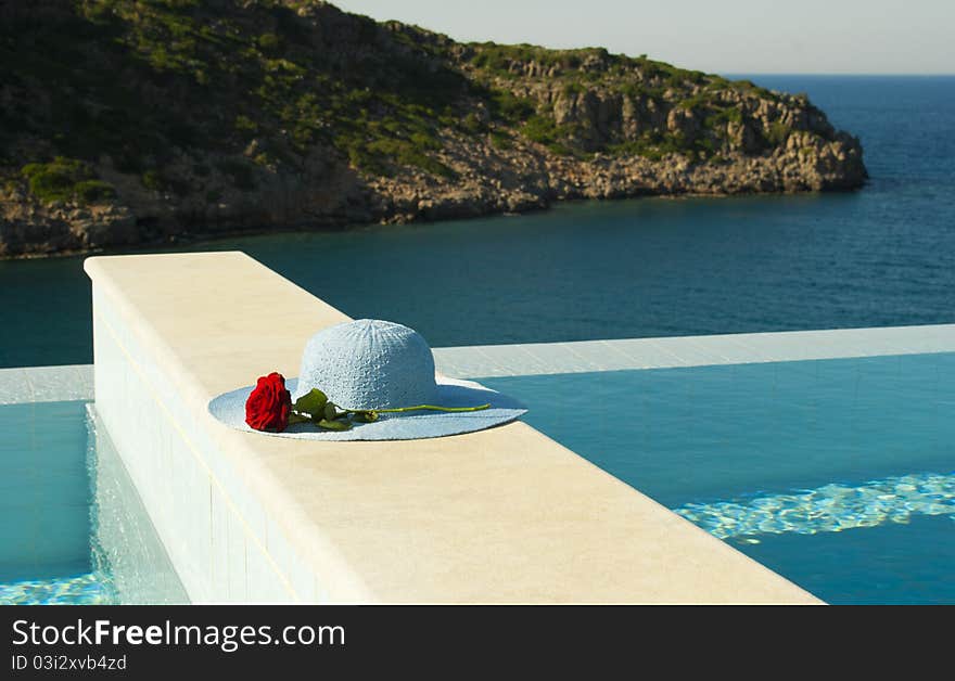 Blue hat and red rose near swimming pool in luxury mediterranian hotel.Crete. Blue hat and red rose near swimming pool in luxury mediterranian hotel.Crete