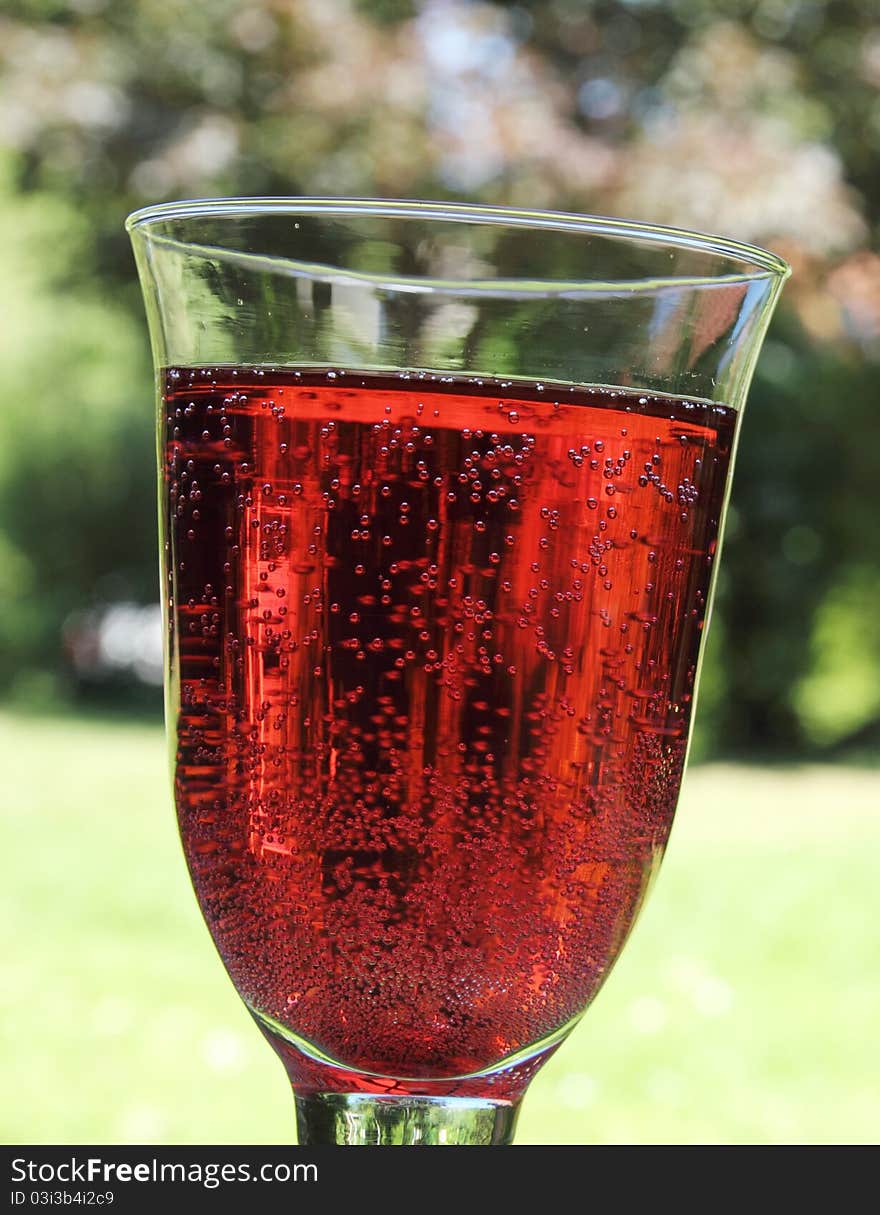 Sweet raspberry soda in a transparent glass on the terrace