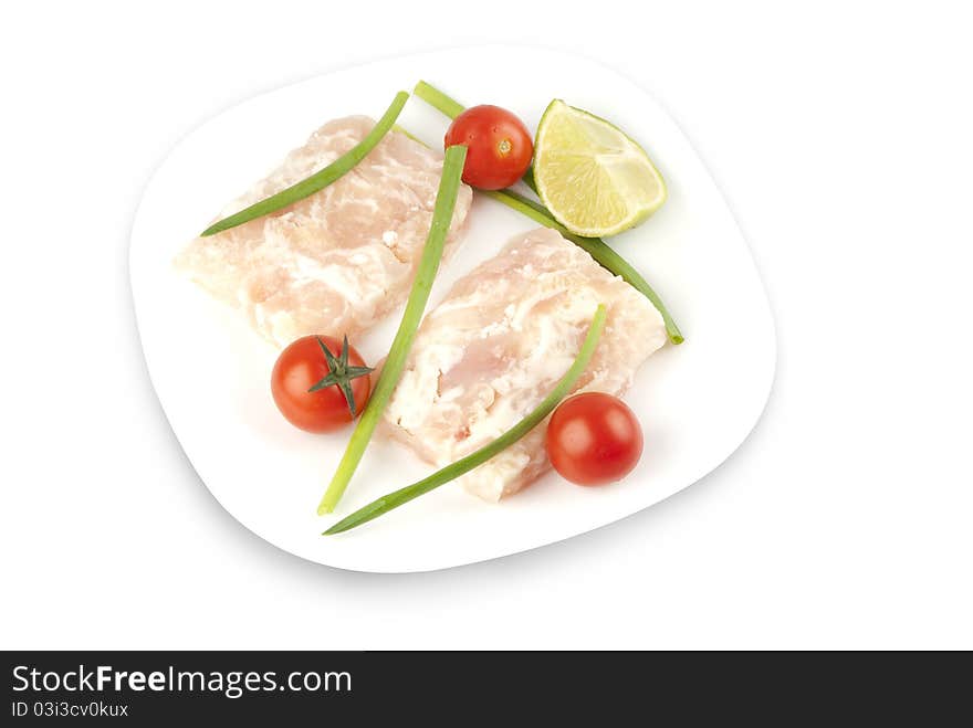 Pangasius fillet molded, decorated with cherry tomatoes with lime and green onions on a white plate