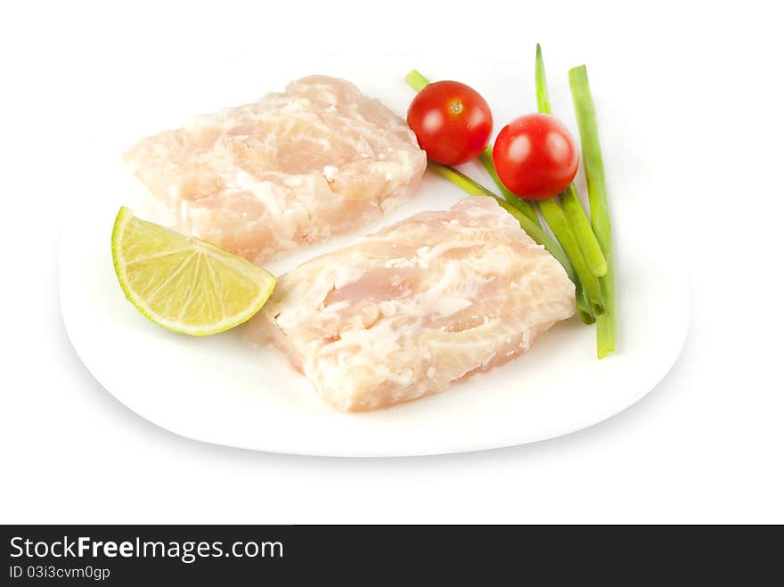 Pangasius fillet molded, decorated with cherry tomatoes with lime and green onions on a white plate