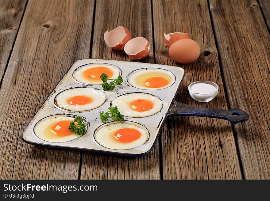 Six fried eggs in an old pan