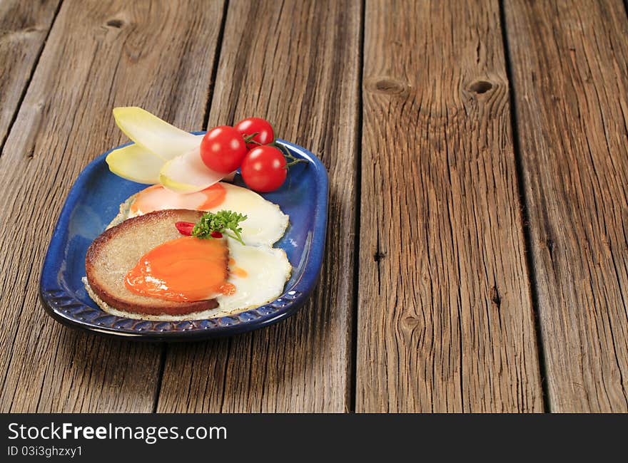 Fried egg and bread and vegetable garnish. Fried egg and bread and vegetable garnish