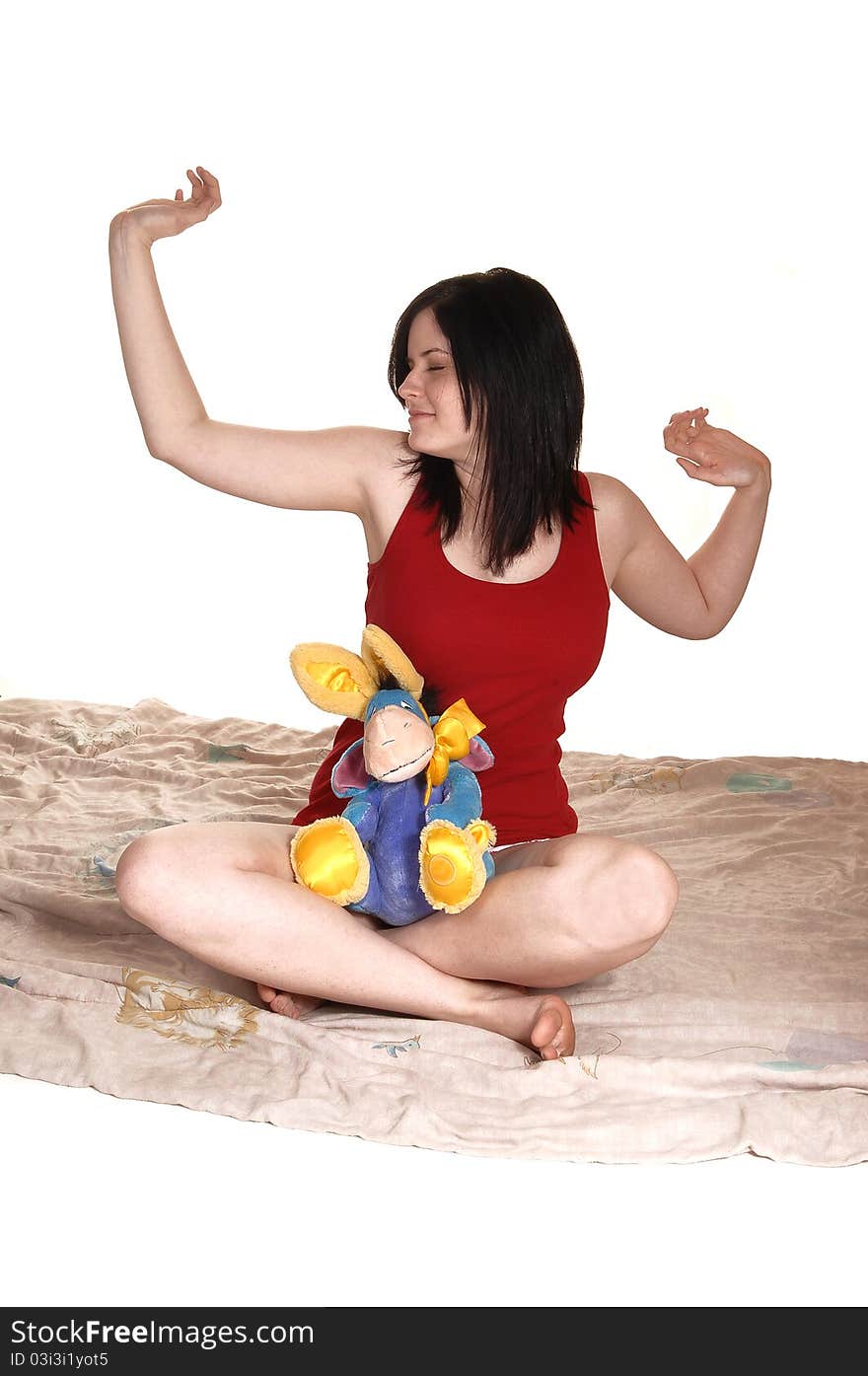 A lovely young woman is stretching after a good night sleep, sitting on her comforter in night wear, for white background. A lovely young woman is stretching after a good night sleep, sitting on her comforter in night wear, for white background.