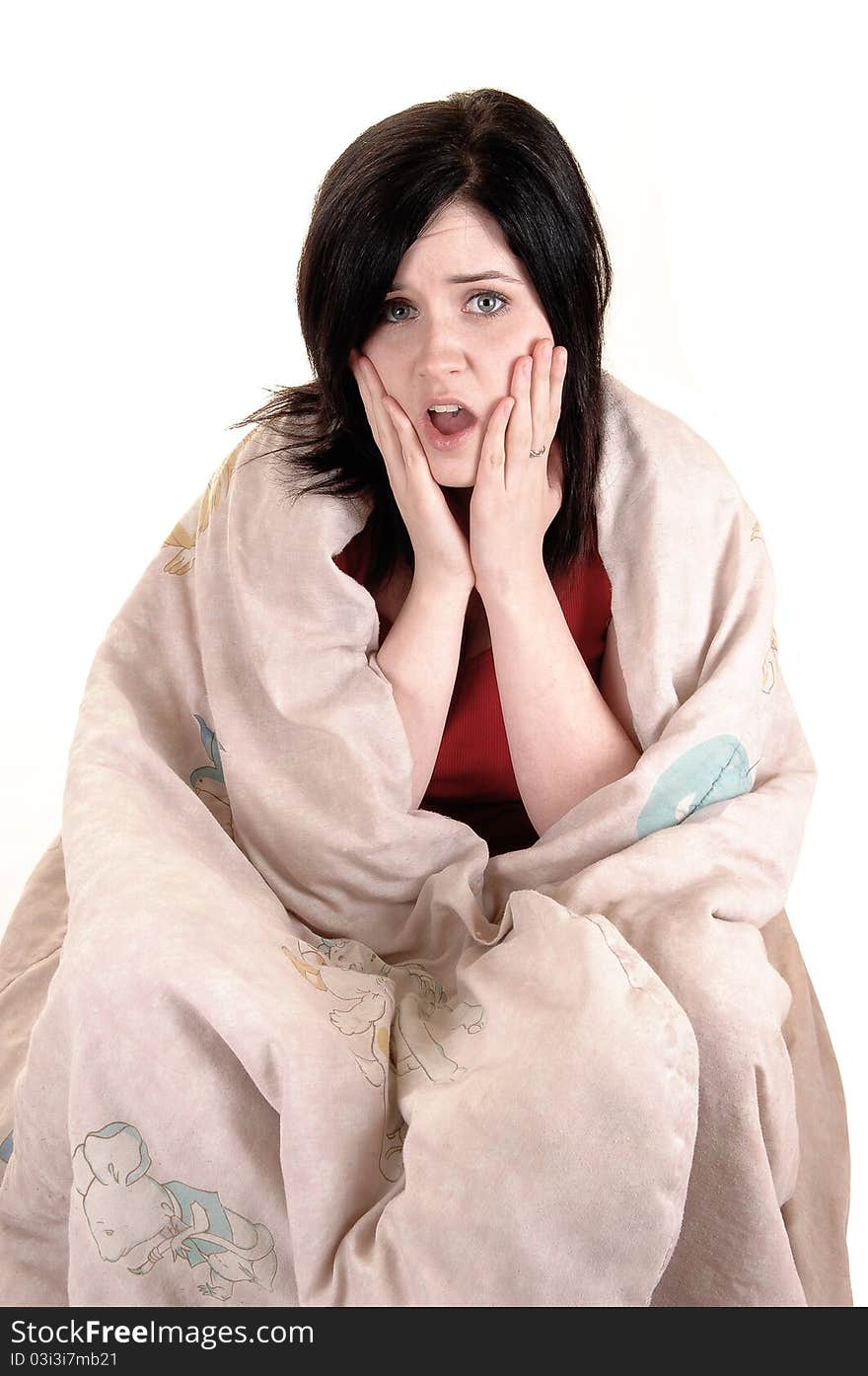 A young girl sitting on the floor covert in a blanket holding her finger to her mouths and thinking hard, for white background. A young girl sitting on the floor covert in a blanket holding her finger to her mouths and thinking hard, for white background.