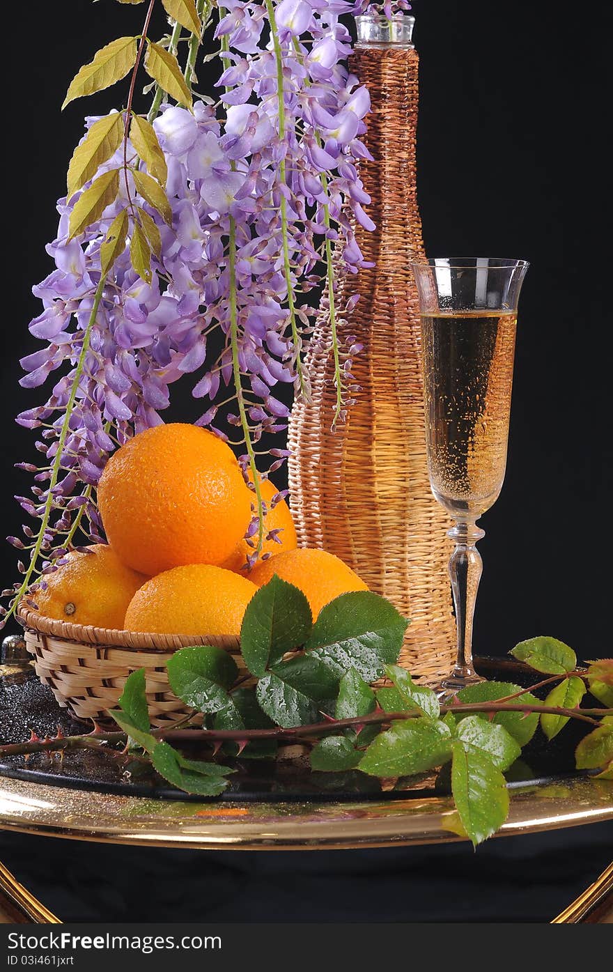 On a round little table a basket with oranges, white wine and a flower Wisteria. On a round little table a basket with oranges, white wine and a flower Wisteria.