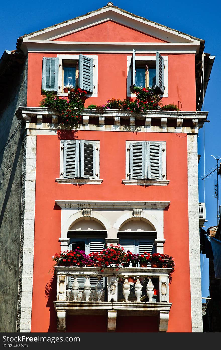 Tall old European house with red walls and stone balcony