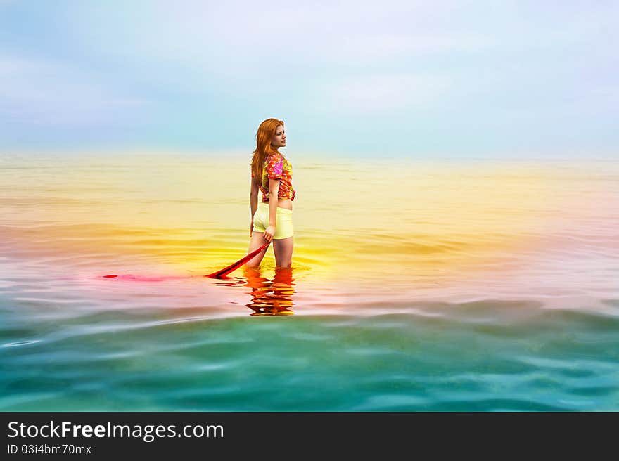 Beautiful sensual woman with red hair in colorful clothes standing and dreaming in the sea. Beautiful sensual woman with red hair in colorful clothes standing and dreaming in the sea