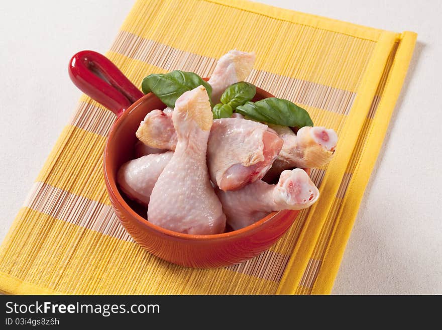 Raw chicken drumsticks in a pan