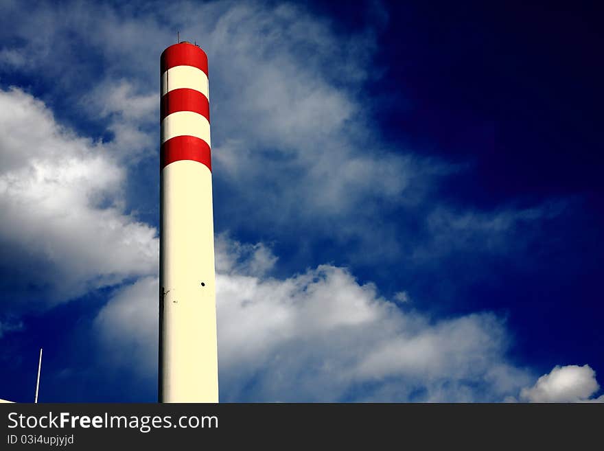 Chimney with red circle under blue sky on the factory