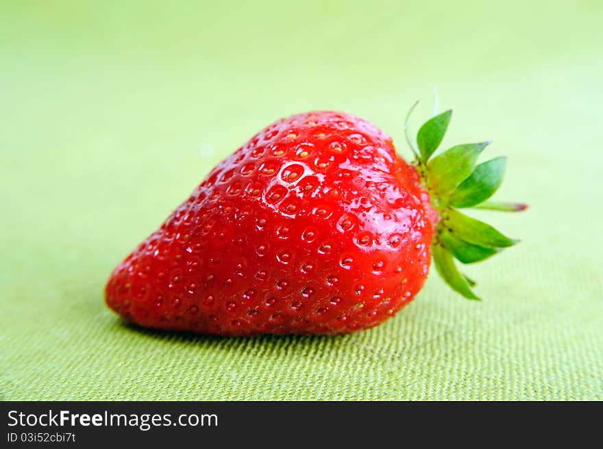 A fresh red strawberry on green background