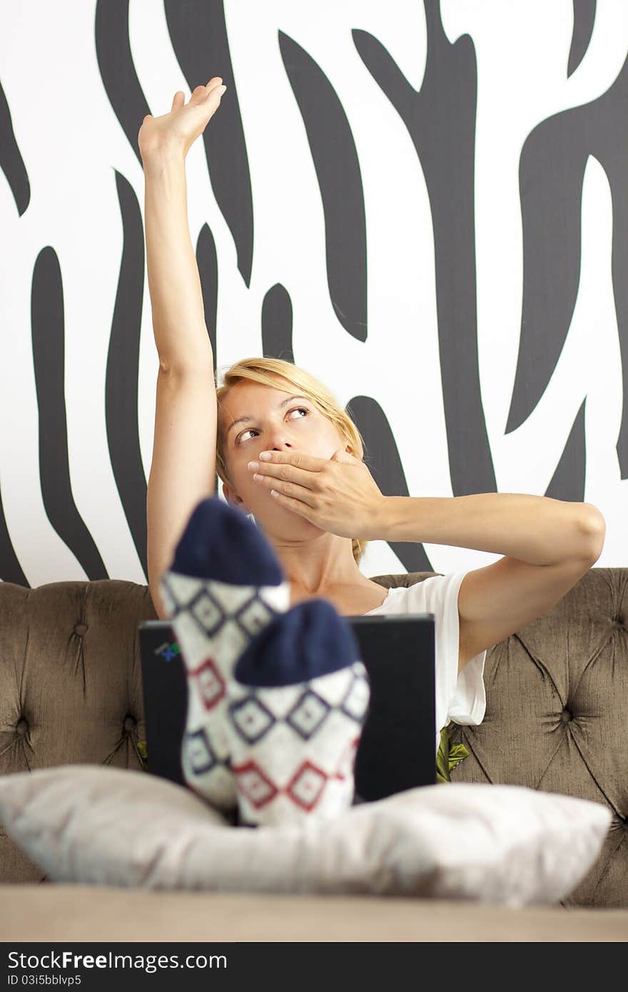 Beautiful young lady using laptop, stretching and yawning