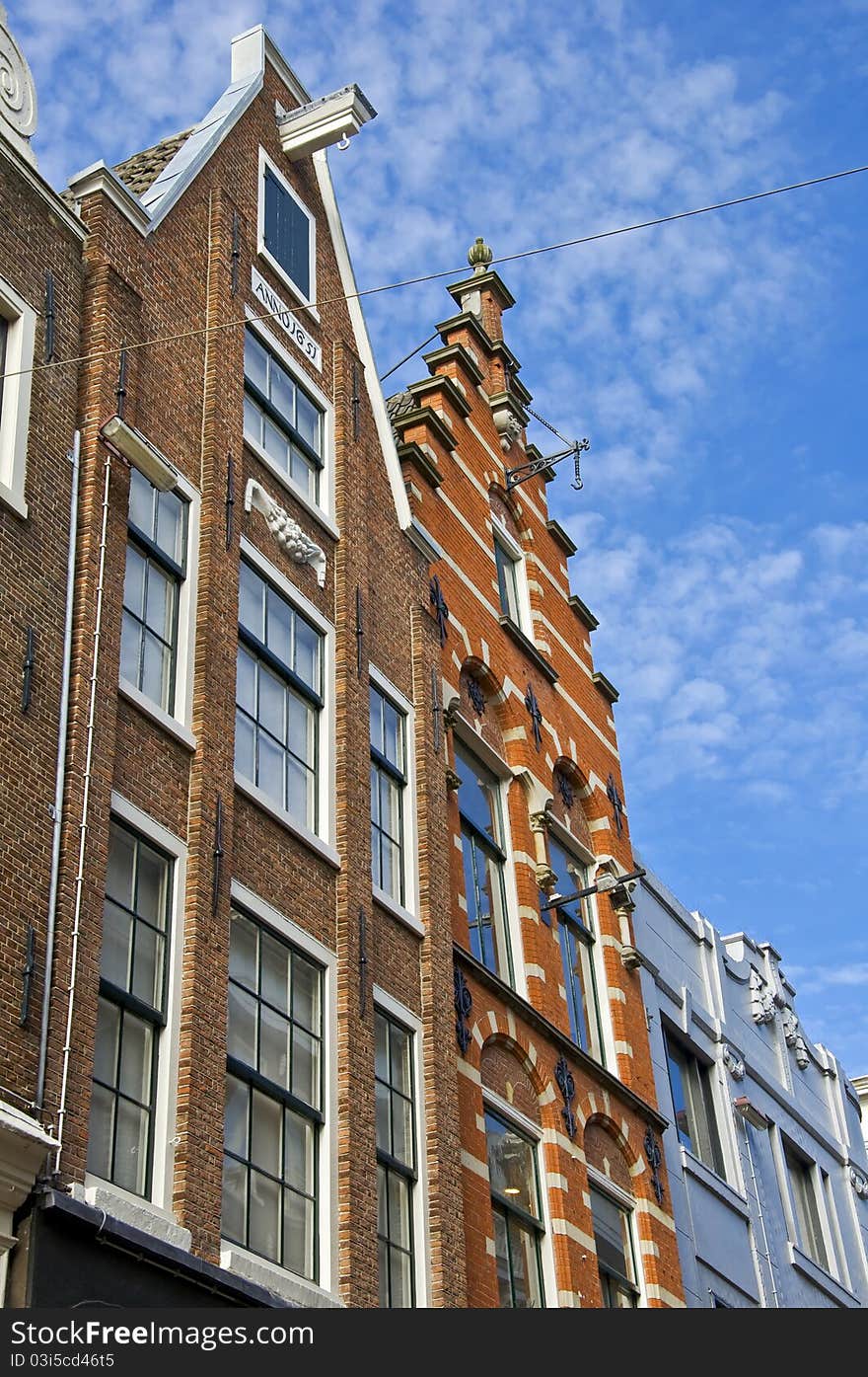 Amsterdam. Dutch houses with a hook at the blue sky. Urban environment of the historical city center.