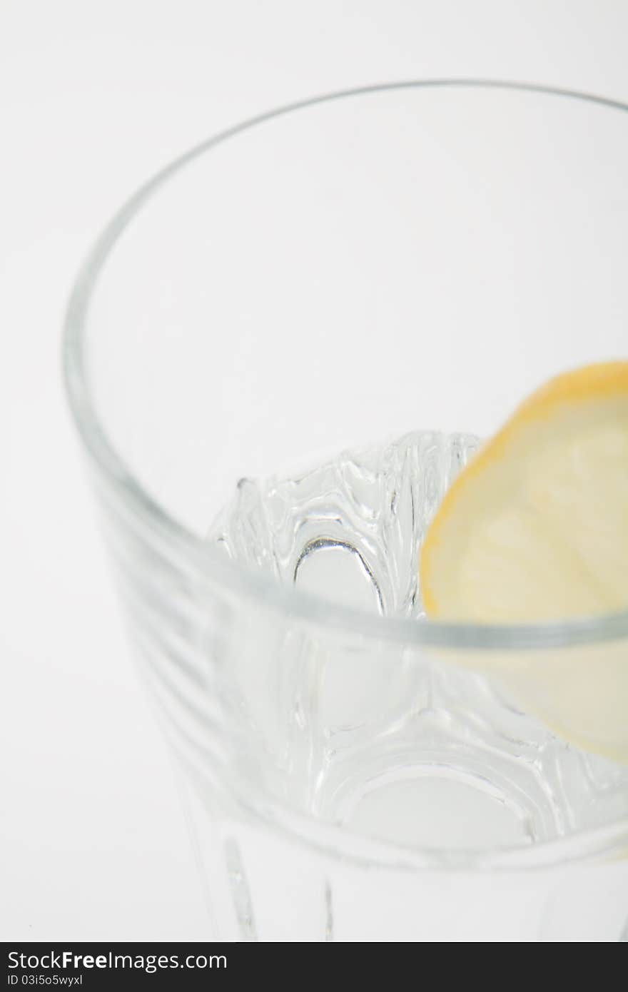 Mineral water in a glass with a lemon on a white isolated background. Mineral water in a glass with a lemon on a white isolated background