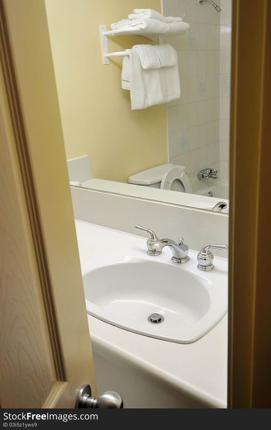 Wooden door opening to white luxurious bathroom. Wooden door opening to white luxurious bathroom.