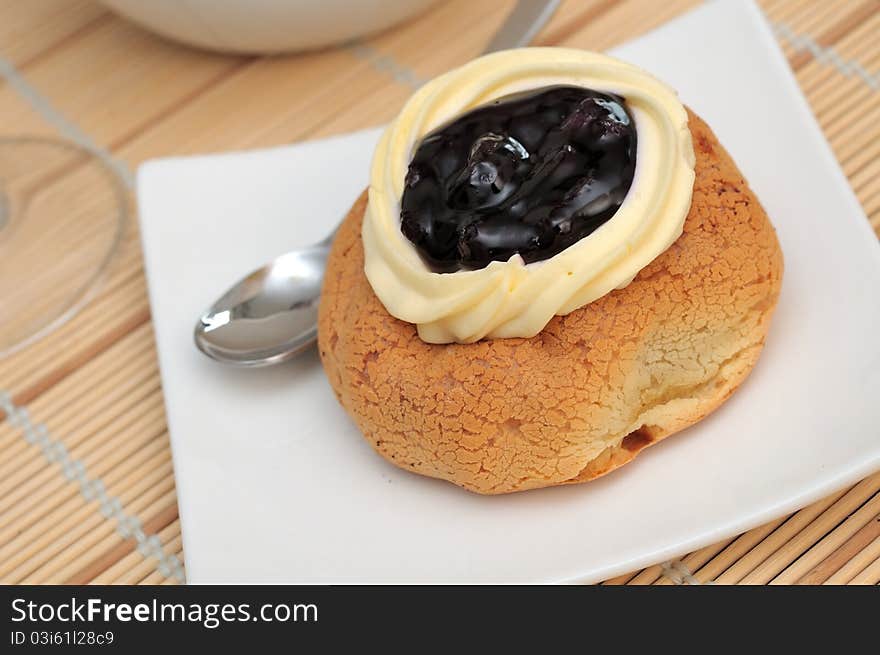 Closeup shot of single muffin with fresh cream topping on white plate. Closeup shot of single muffin with fresh cream topping on white plate.