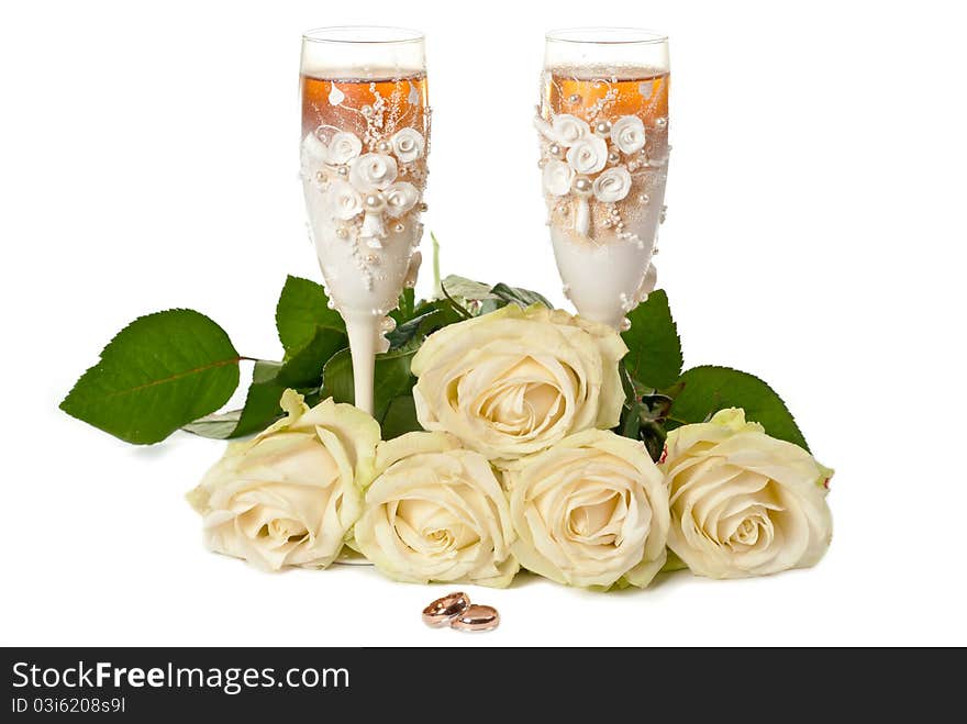 Two glasses of celebratory champagne with white roses and rings. Two glasses of celebratory champagne with white roses and rings