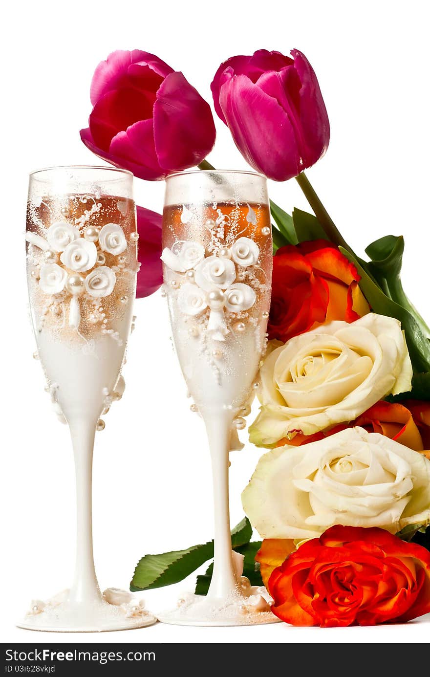 Two glasses of celebratory champagne with roses and tulips. Isolated on white. Two glasses of celebratory champagne with roses and tulips. Isolated on white