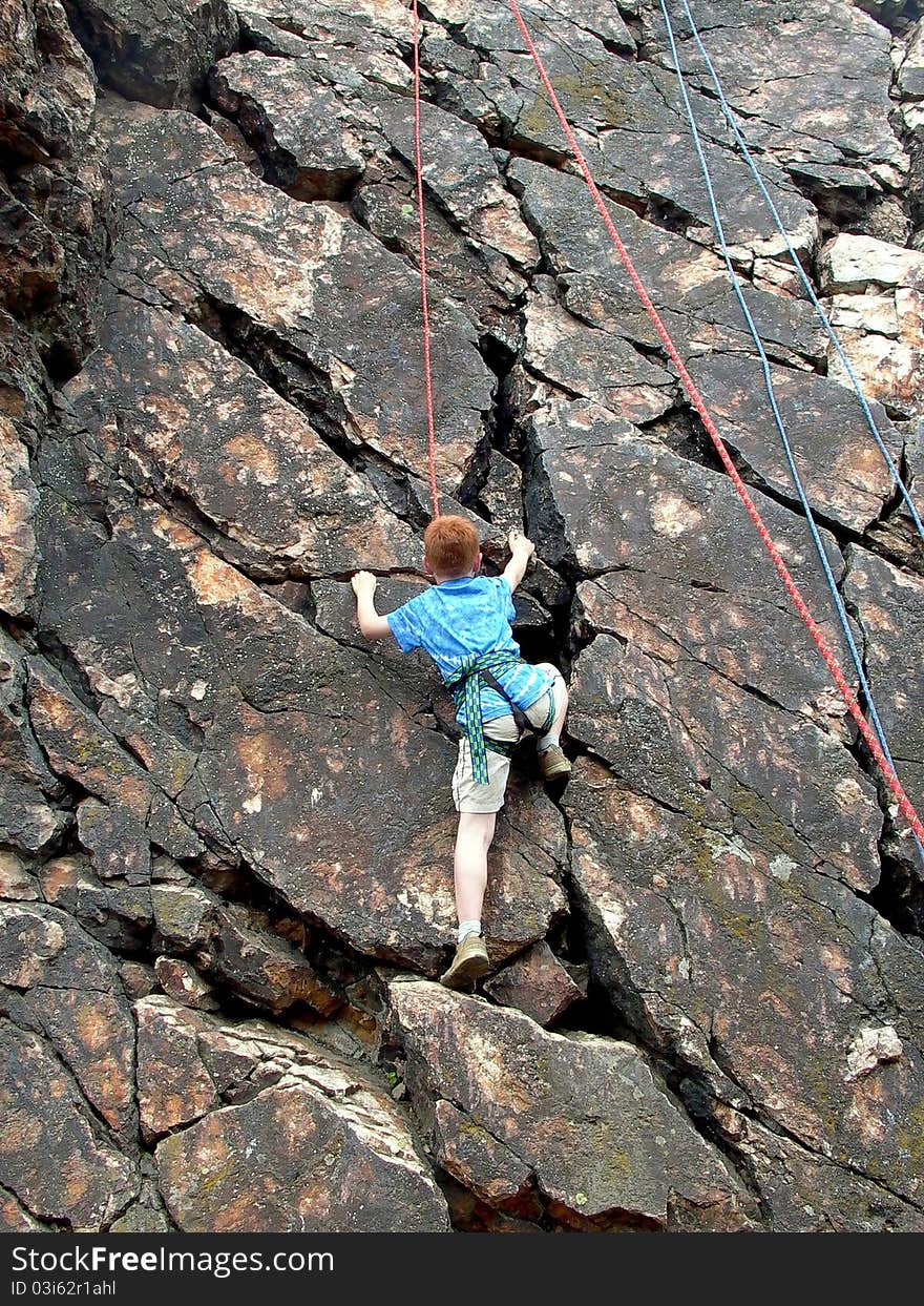 Boy climbing on rope at the rock