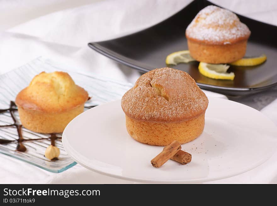 Cinnamon muffin on a cake stand and assorted muffins out of focus in the background. Selective focus, shallow DOF