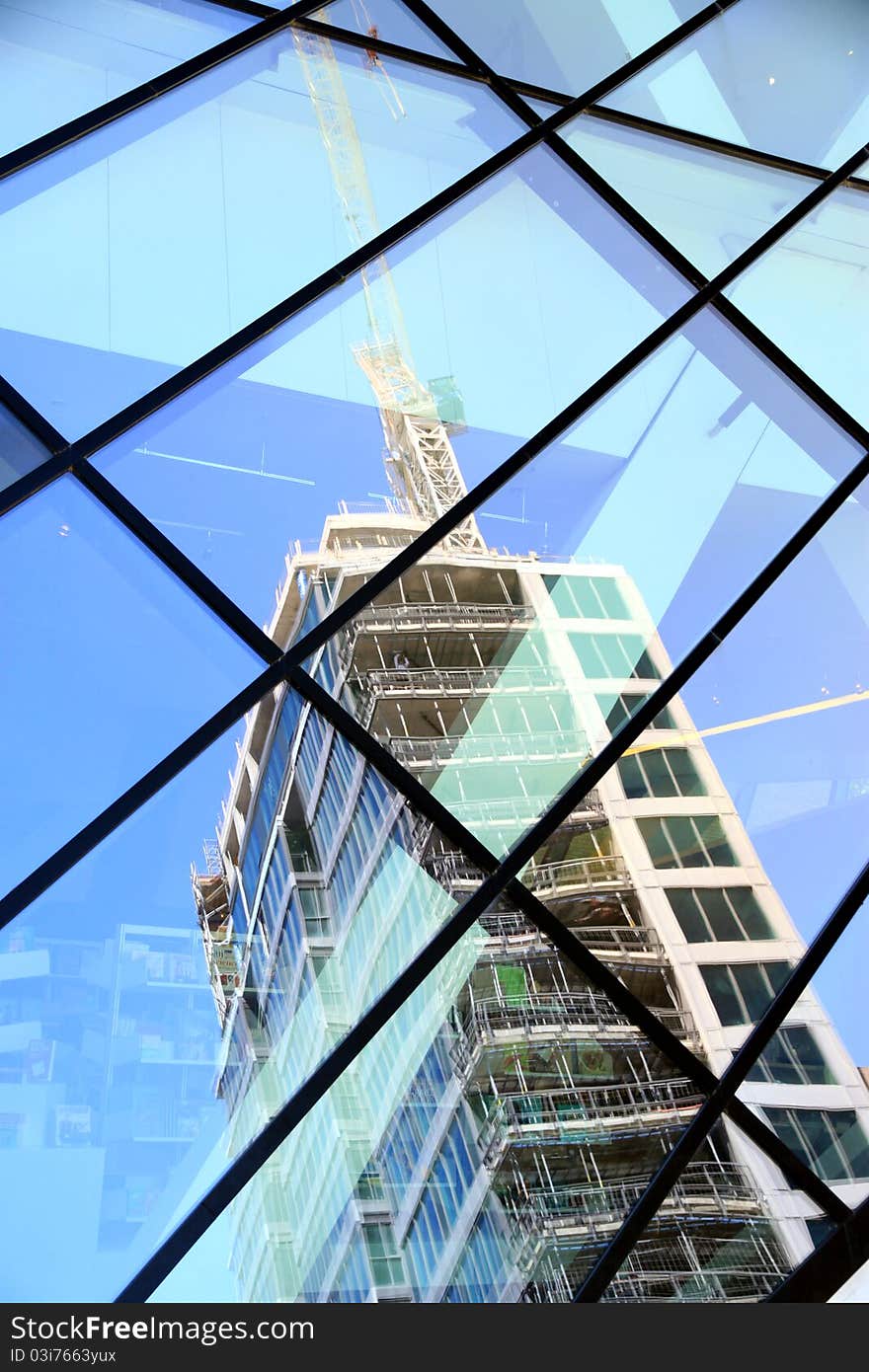 A building under construction reflected in a glass structure