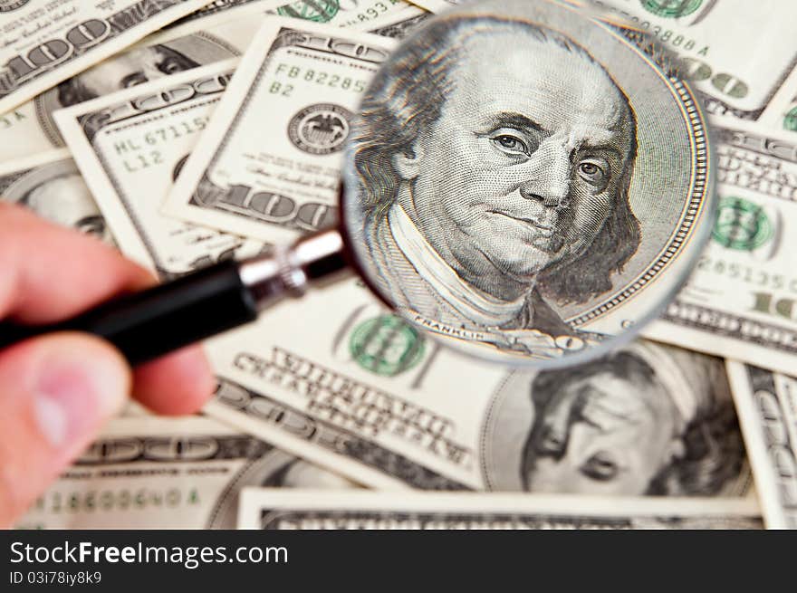 Magnifying glass lies on  american dollars on white