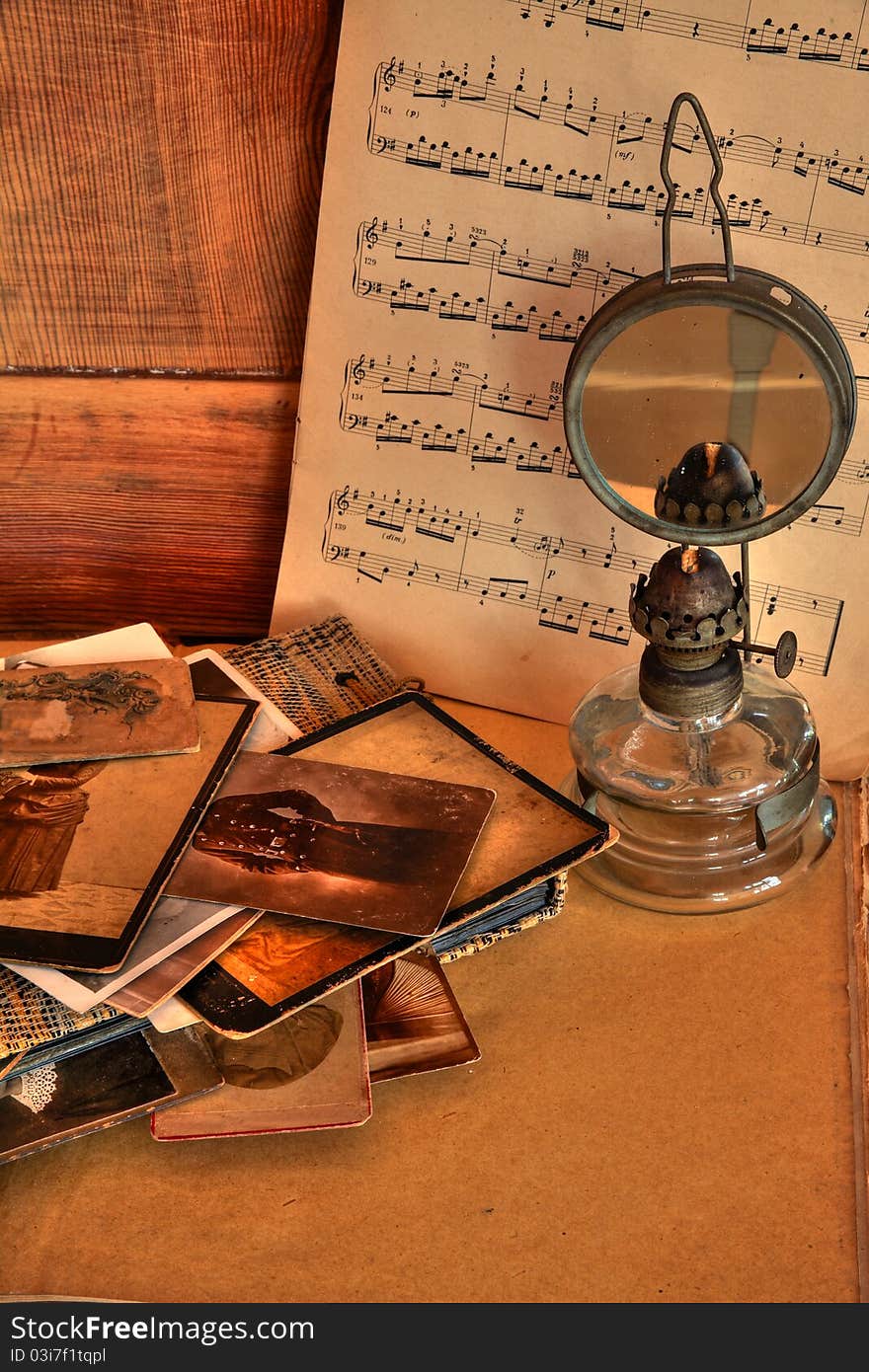 Stack of old photos, album and oil lamp, note on wooden background. Stack of old photos, album and oil lamp, note on wooden background.