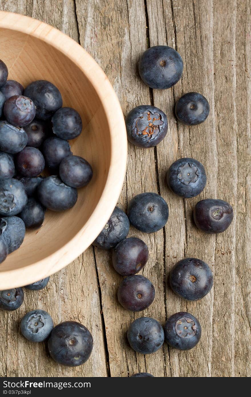 Top view on wooden bowl with fresh blueberry on old wooden table