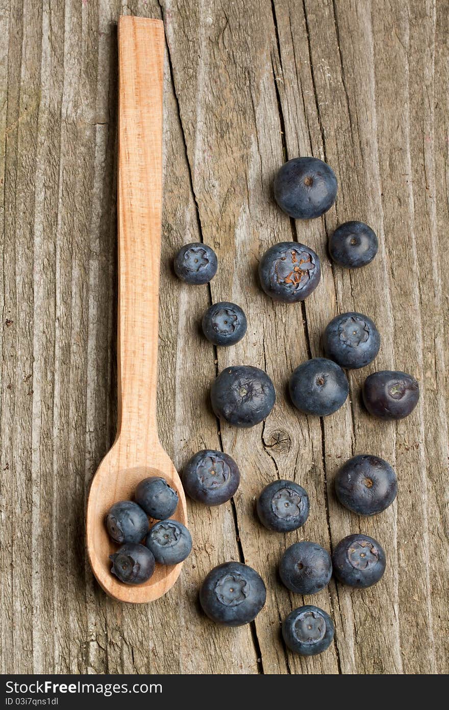 Top view on wooden spoon with fresh blueberries on old wooden table