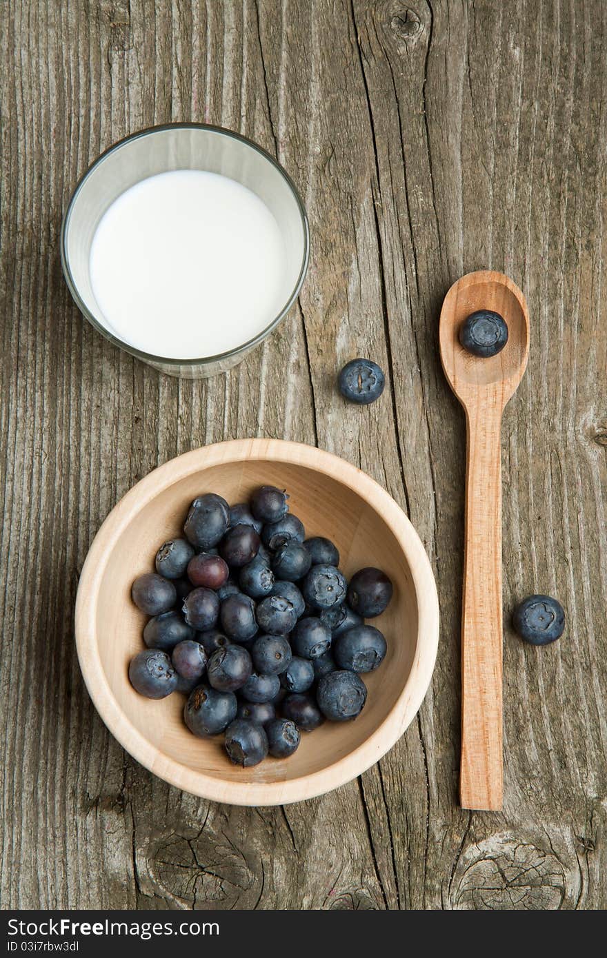 Bowl of fresh blueberries and glass of milk