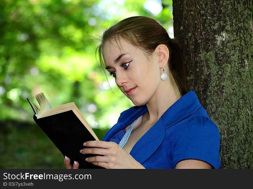 Beautiful girl  teenager reads the book in park