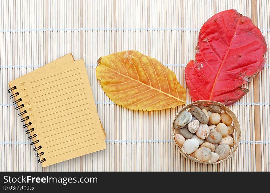 Brown notebook with line over wooden plate and dry leaf red and yellow