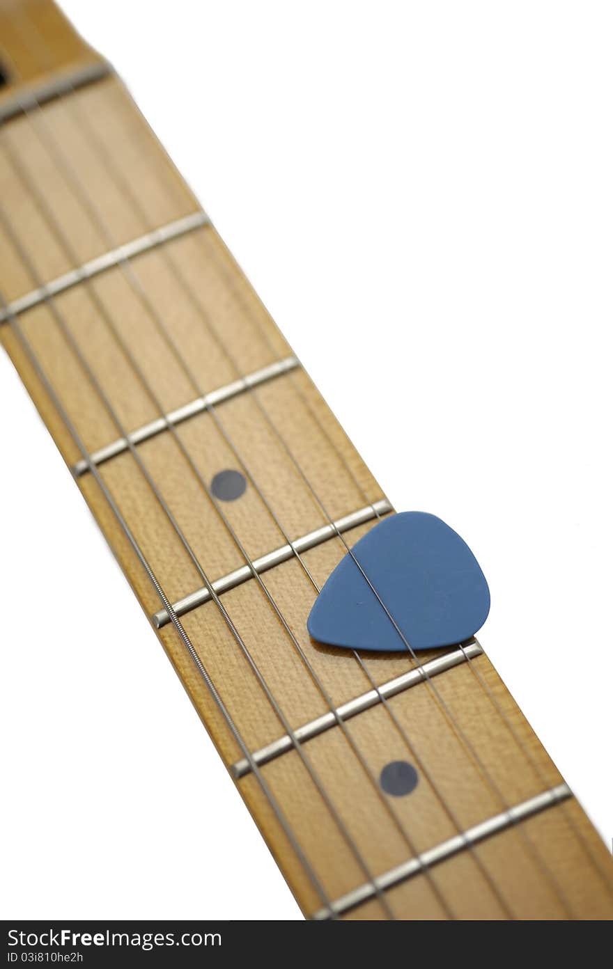 Blue guitar pick held between three strings on the neck of an electric guitar with maple fretboard. Isolated on white background with clipping path.