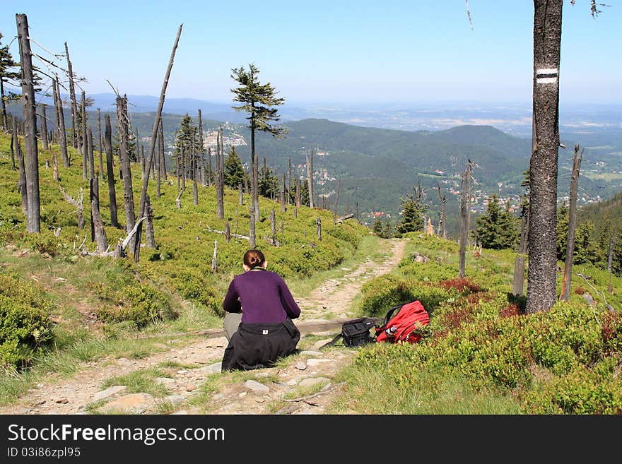 Young woman traveler rests on a mountain trail while hiking.