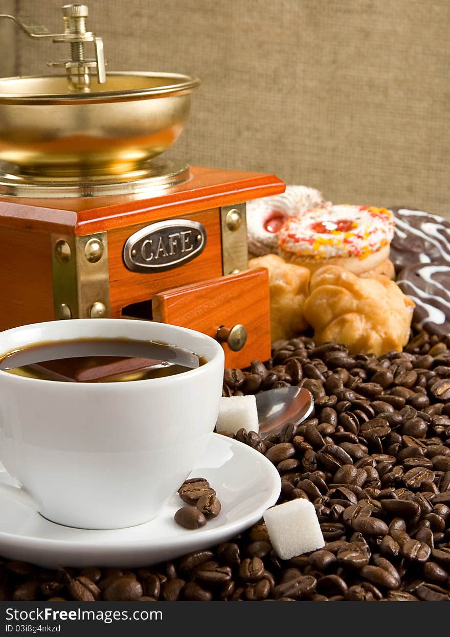 Cup full of coffee, beans, pot and grinder