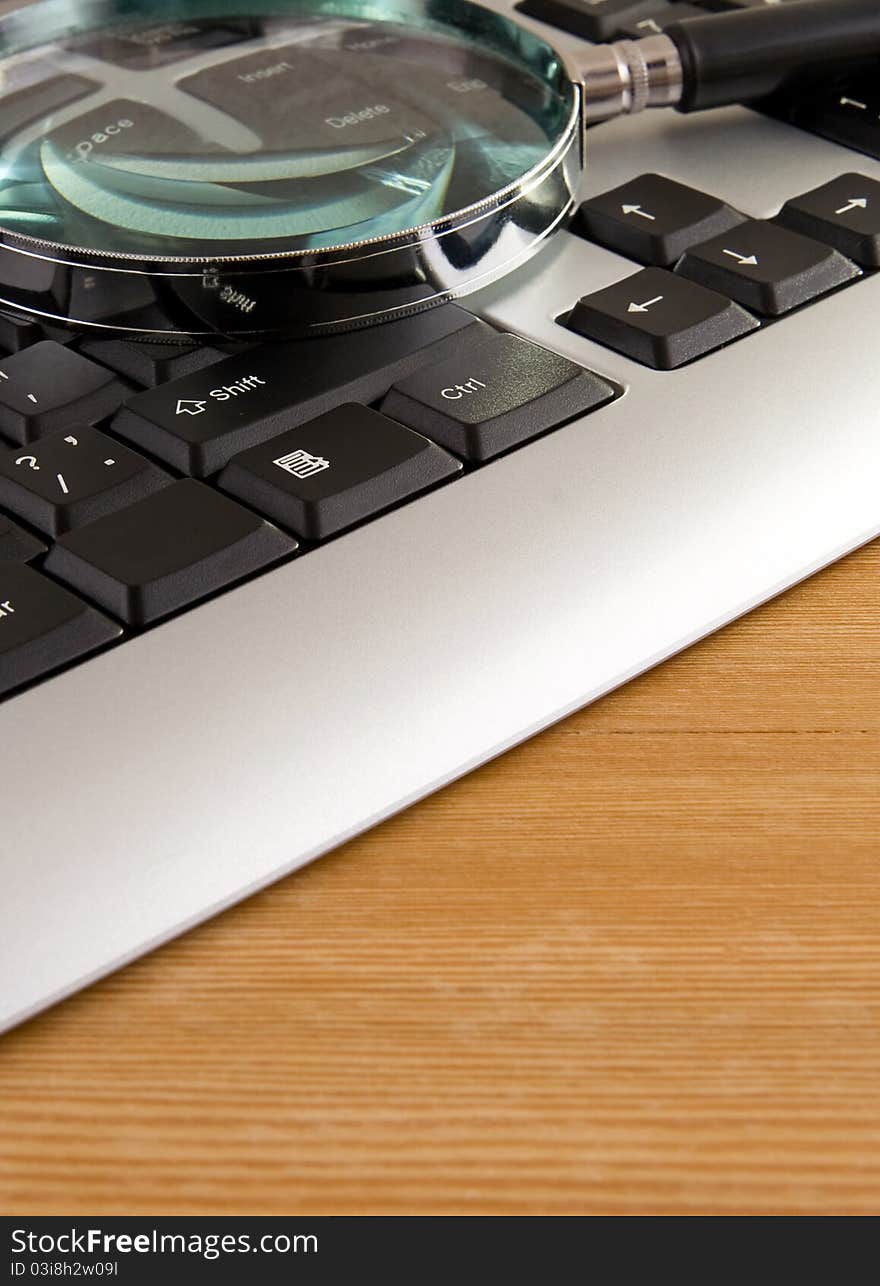 Magnifier and laptop with on wooden table