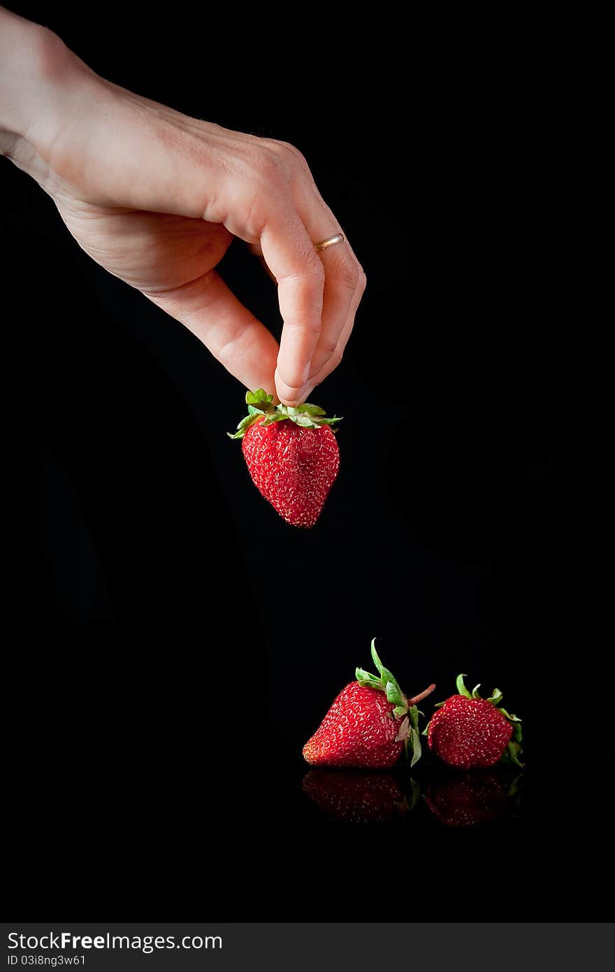 Hand with red strawberry isolated on black. Hand with red strawberry isolated on black