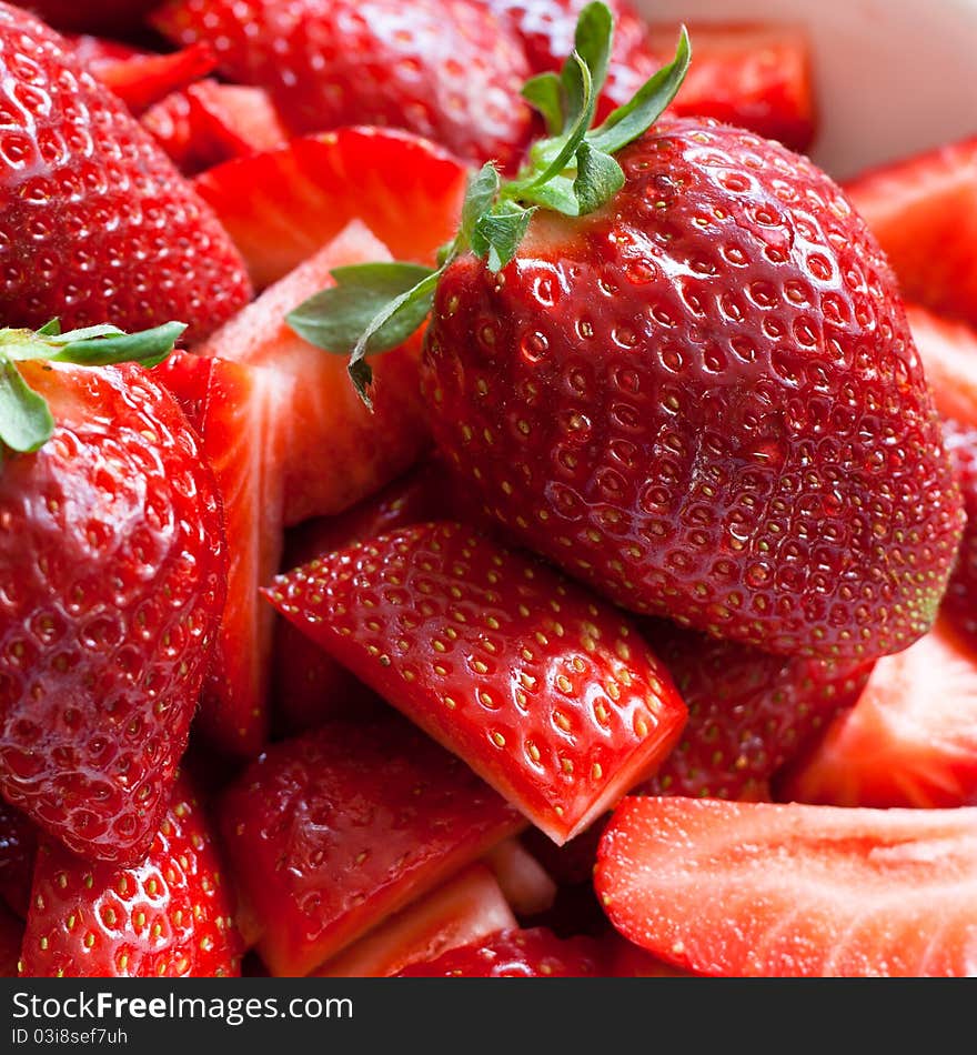 A bowl full of fresh strawberries, cut into pieces