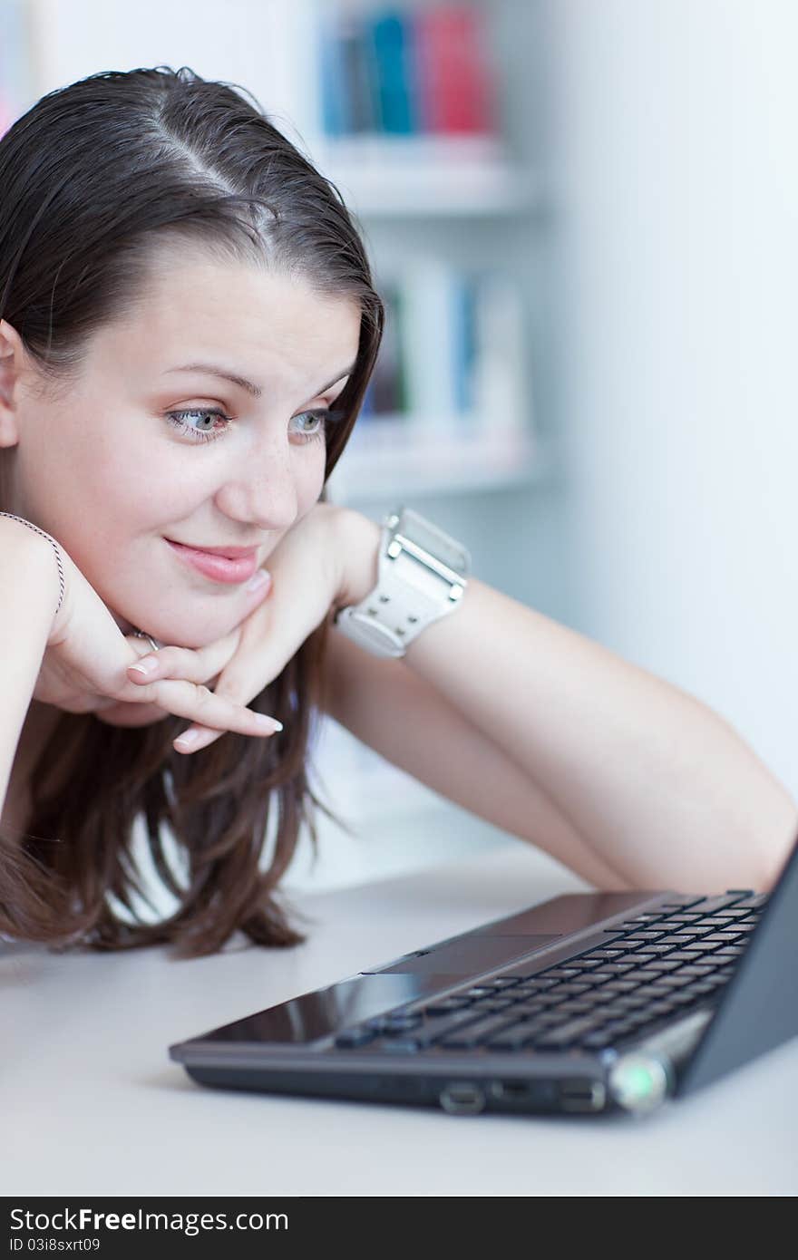 In the library - pretty female student with laptop and books working in a high school library (color toned image)