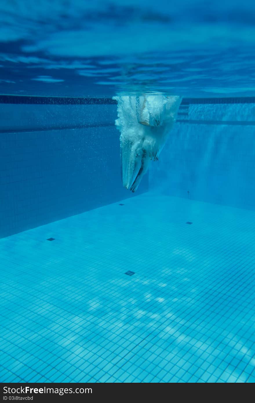 Platform diver under water in outdoor pool