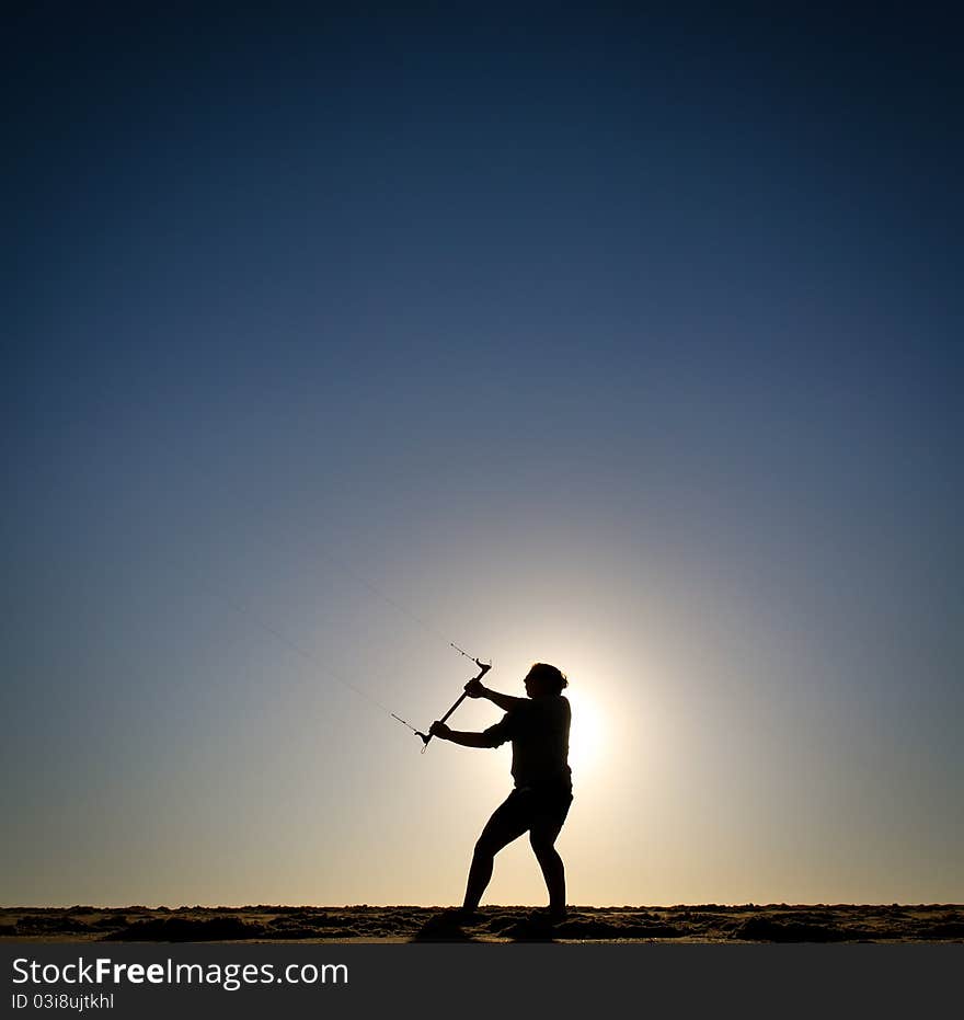 Silhouette of girl flying kite at sunset